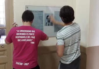 Dos estudiantes mirando la placa